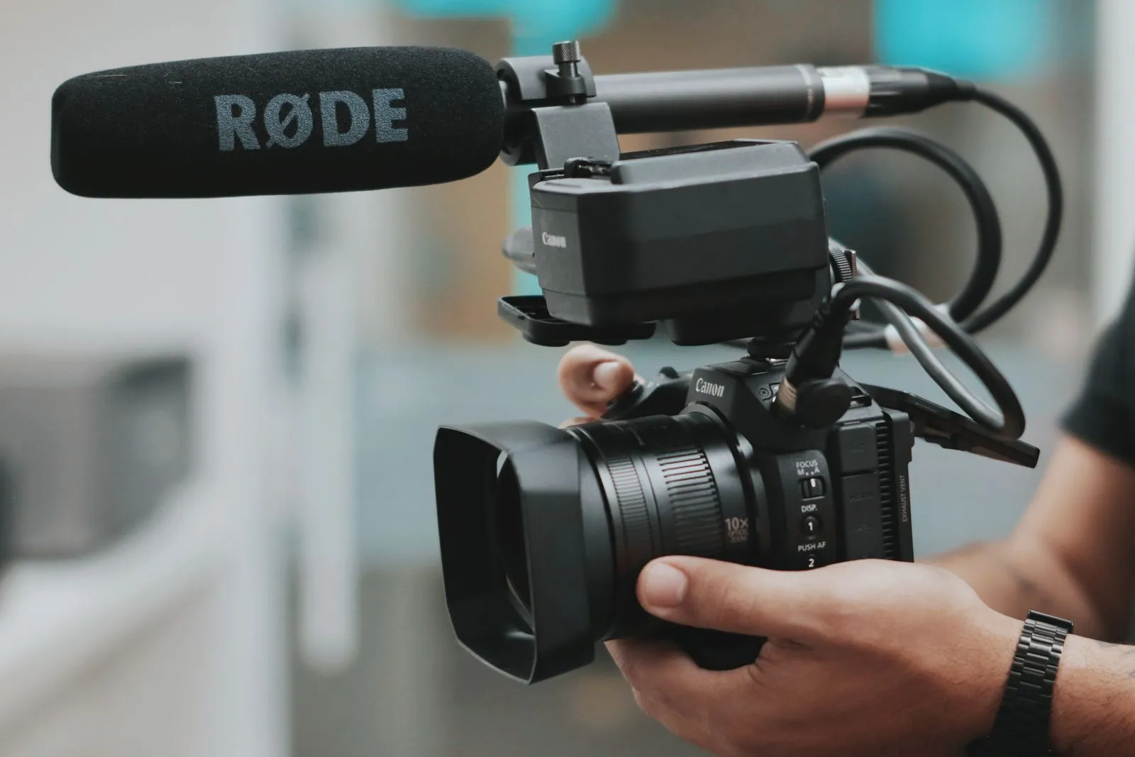 Handheld video camera with a microphone mounted above the lens.