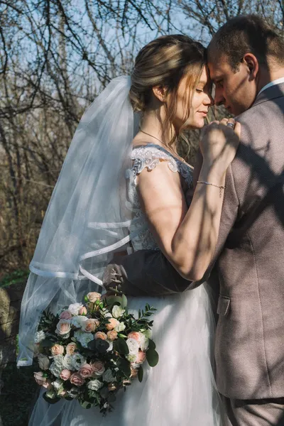 Couple in wedding attire standing close together in a garden.