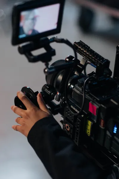Hands operating a video camera fitted with an external monitor.