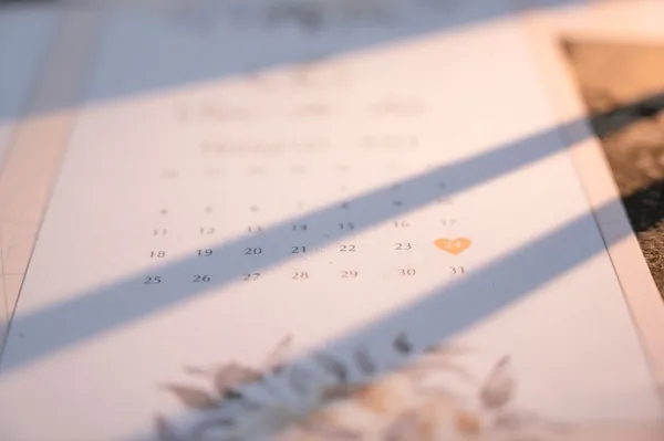 Close view of a calendar lit by light from a window.