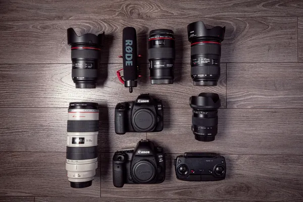 Camera bodies and photographic lenses arranged on a wooden table.