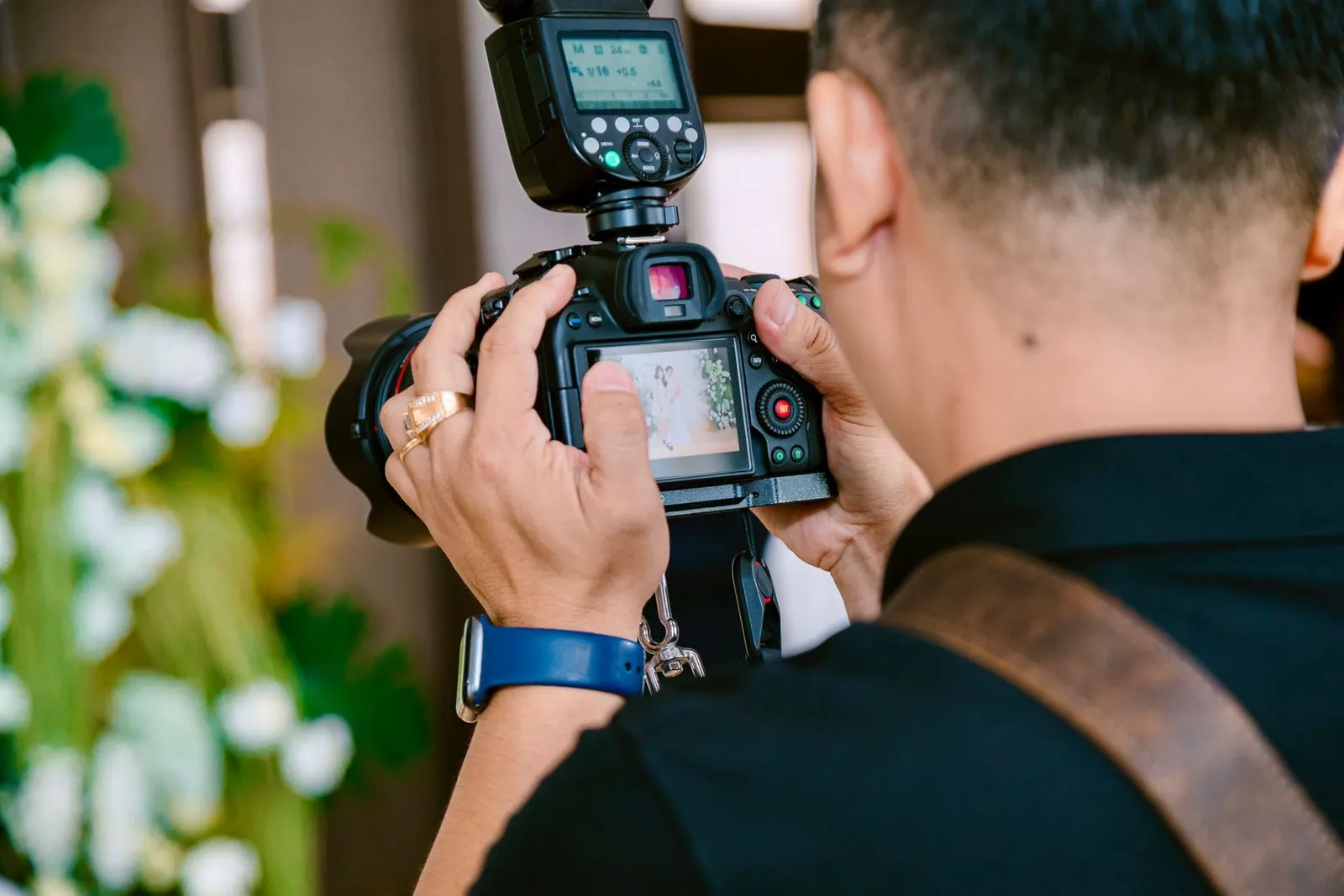Photographer seen from behind holding a camera fitted with a flash.