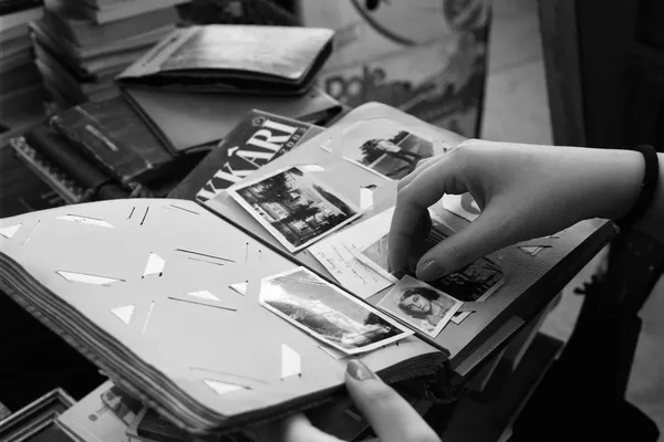 Black and white photograph of hands turning the pages of a photo album.