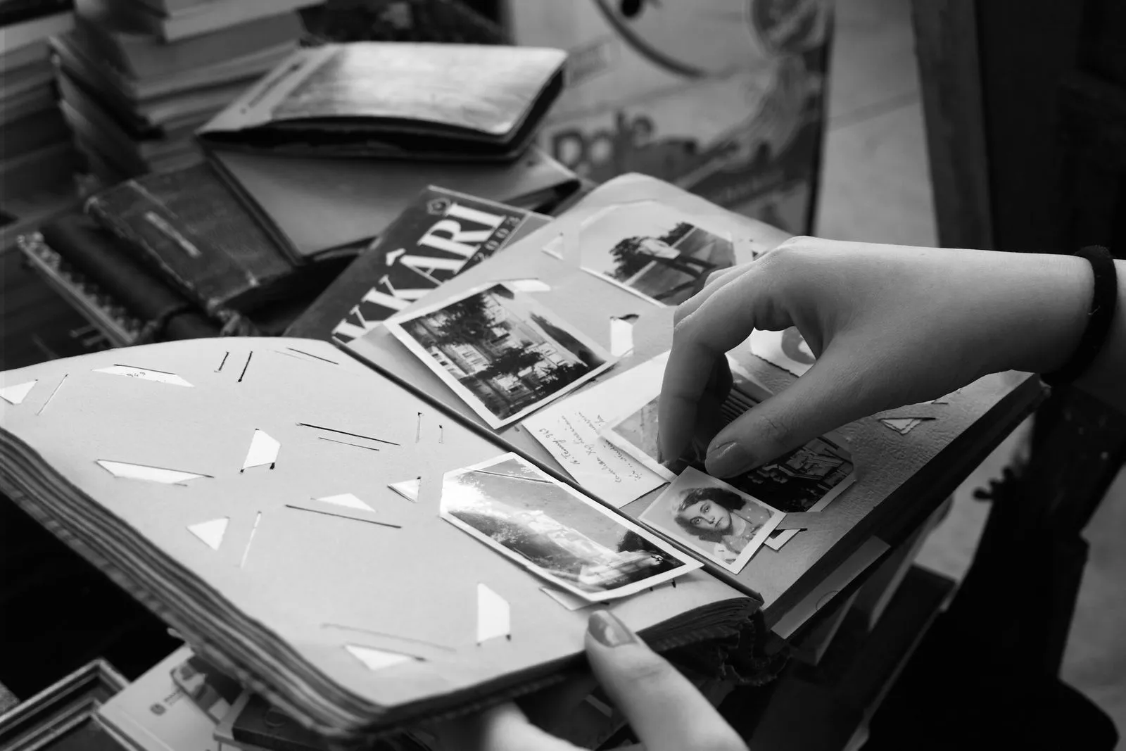 Black and white photograph of hands turning the pages of a photo album.