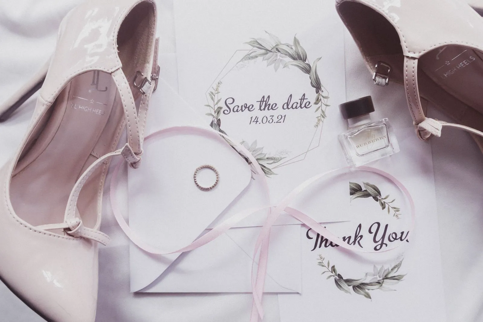 Bridal shoes and wedding stationery on light fabric.