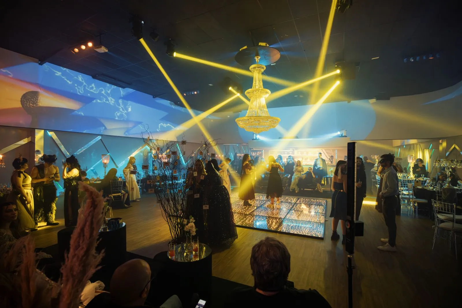 Invités réunis autour d’une piste de danse éclairée de faisceaux lumineux.