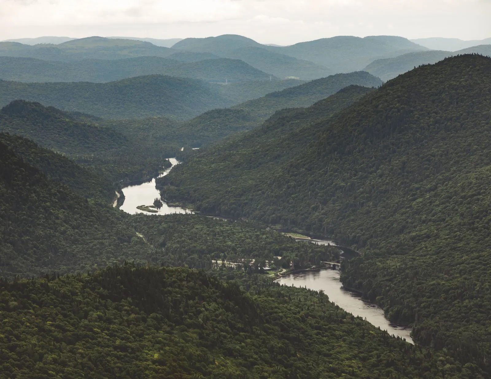 Paysage de montagnes boisées traversé par un cours d’eau.