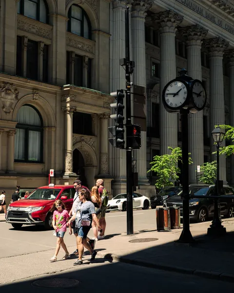 Pedestrians crossing a busy street in Old Montreal, Canada, under the summer sun.