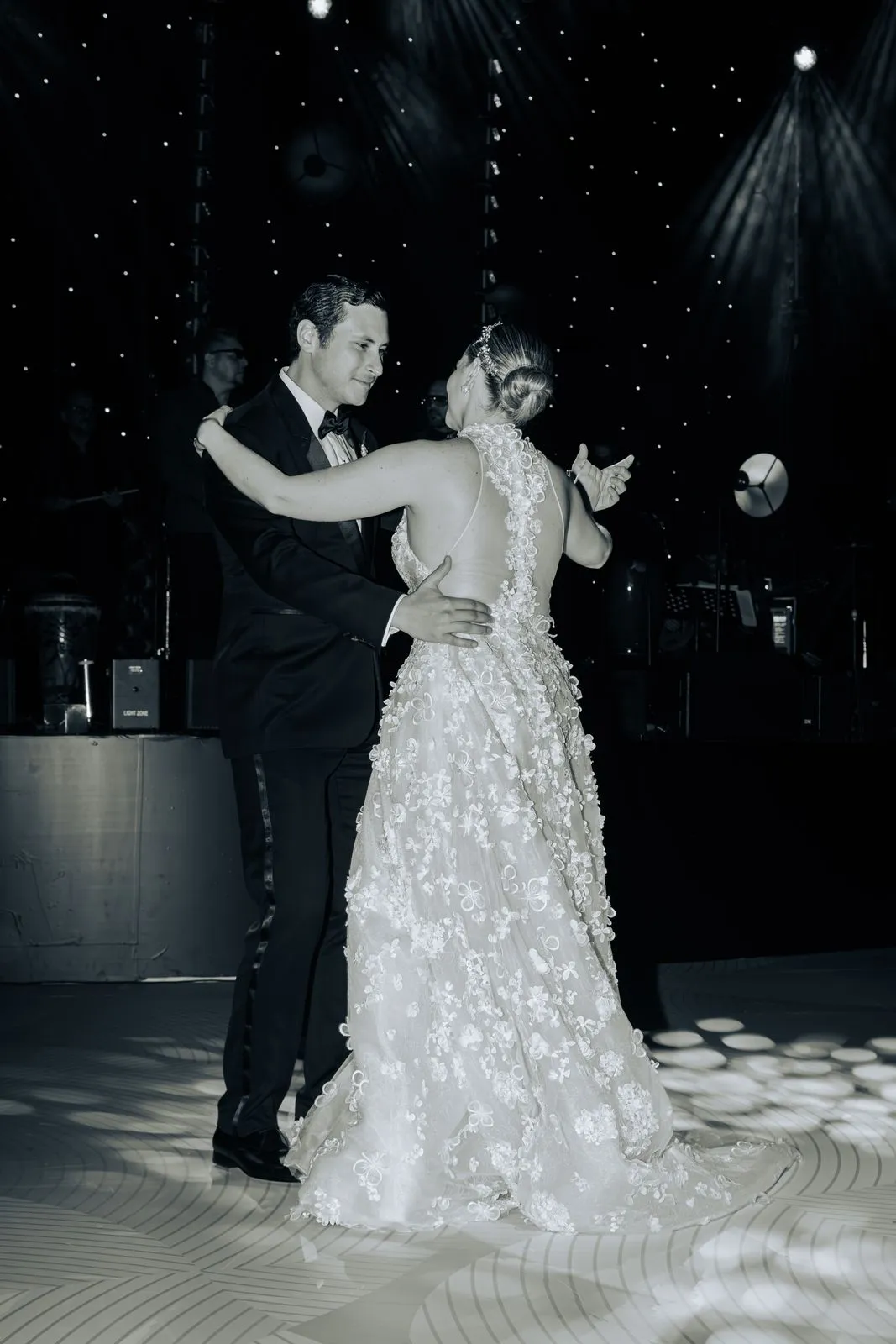 A couple dances gracefully at their wedding reception, surrounded by shimmering lights.
