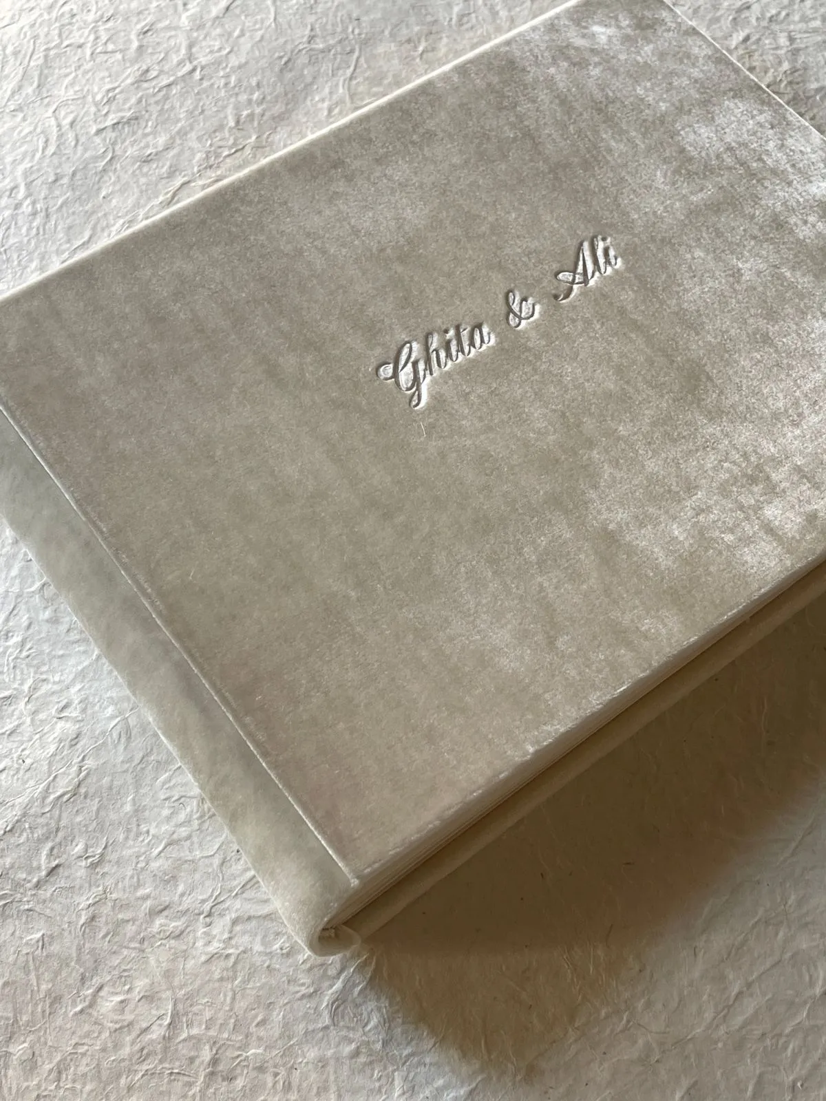 A luxurious velvet-covered wedding album resting on a textured surface, showcasing personalized embroidery.