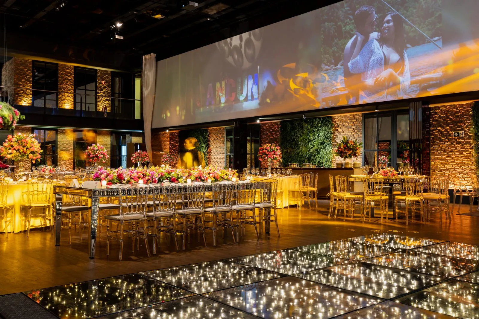 Salle de réception éclairée aux tons dorés avec un décor de tables fleuri.