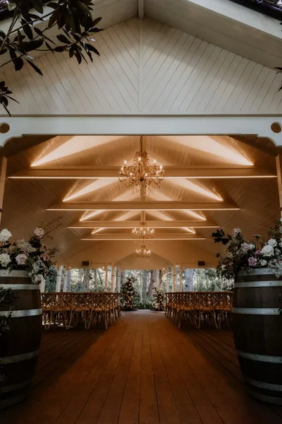 A beautifully decorated rustic wedding hall featuring floral arrangements and chandeliers.