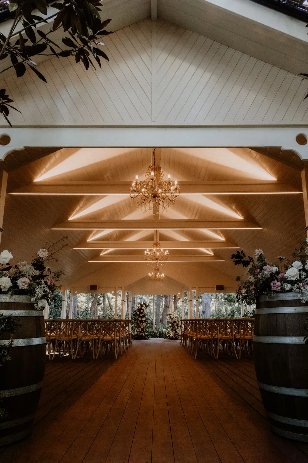 A beautifully decorated rustic wedding hall featuring floral arrangements and chandeliers.