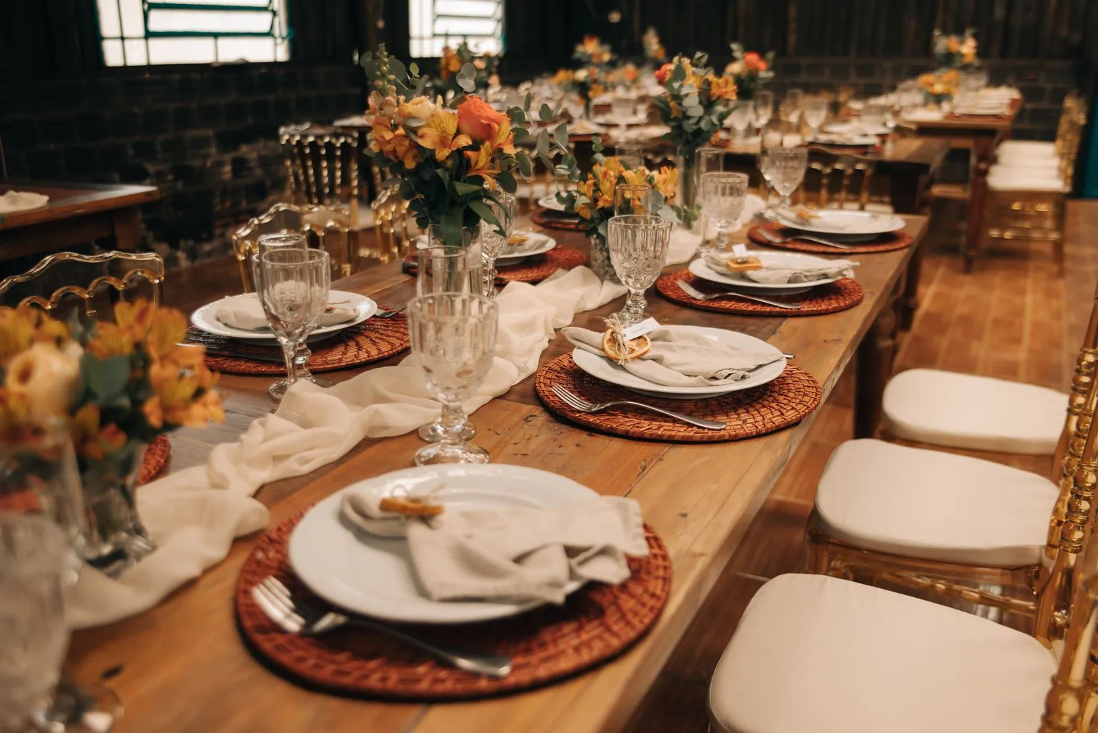 Grande table de réception avec compositions florales, assiettes et couverts.