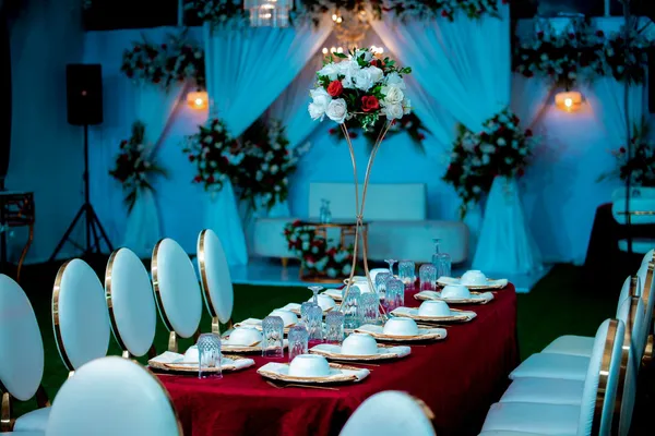 Beautifully decorated table setting for a wedding reception with floral centerpiece and elegant backdrop.