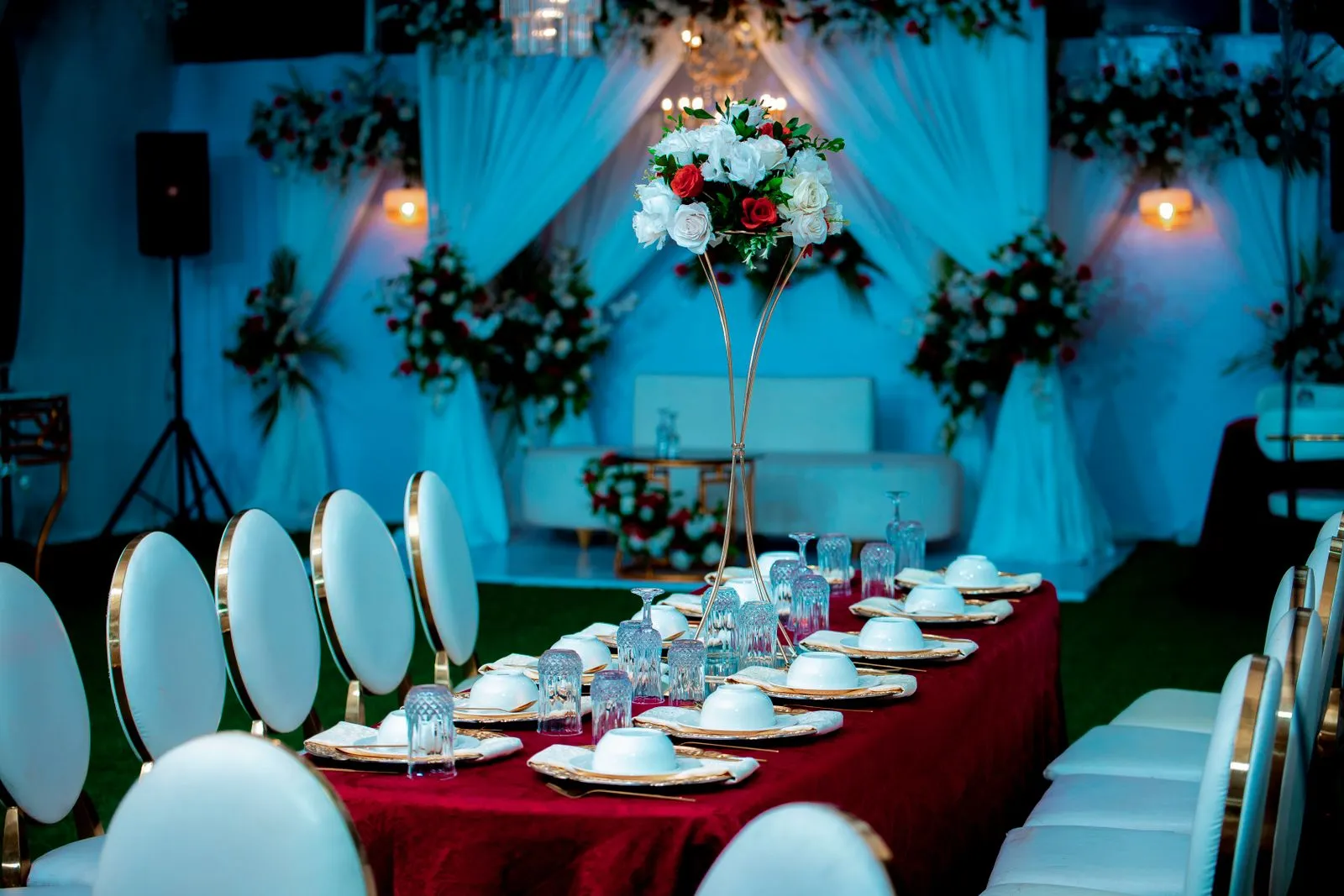 Beautifully decorated table setting for a wedding reception with floral centerpiece and elegant backdrop.