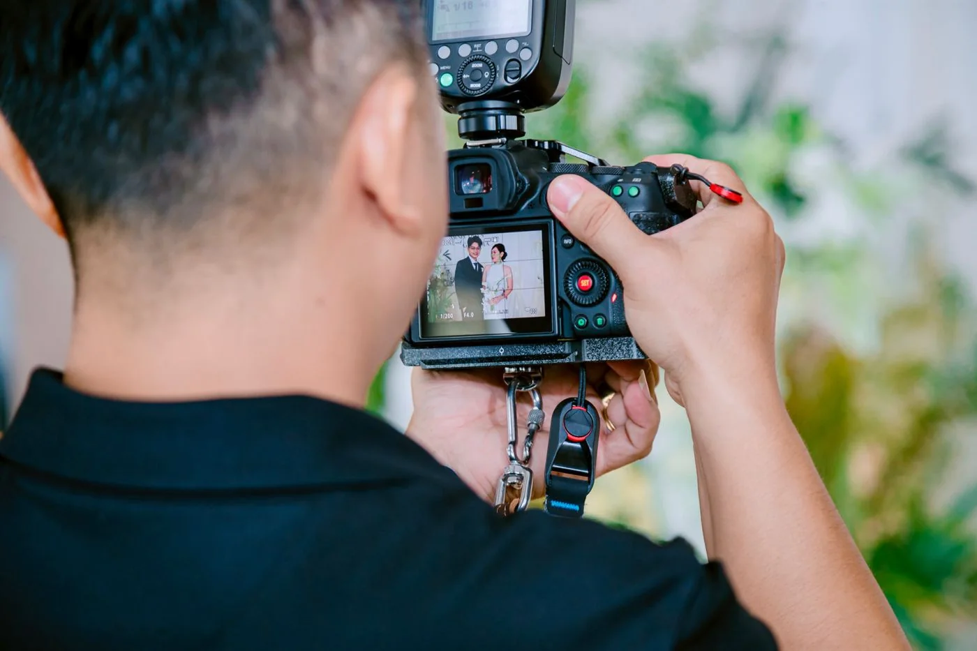Un photographe tient un appareil dont l’écran montre un couple de mariés.