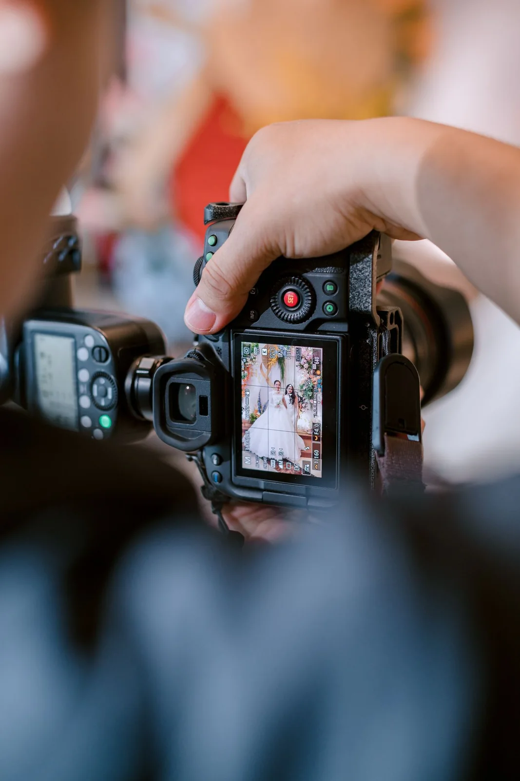 Gros plan sur les mains d’un photographe et l’écran de son appareil pendant un mariage.