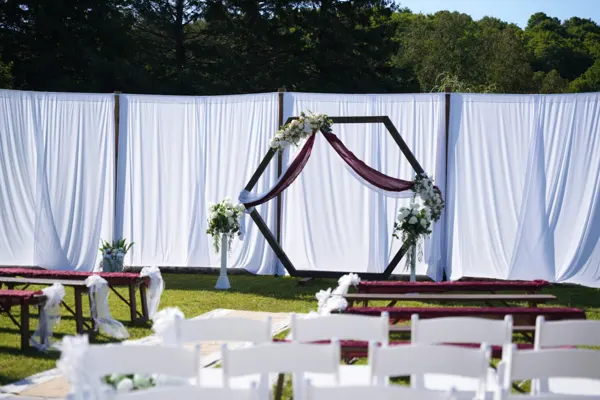 Chairs and a draped arch await guests at an outdoor ceremony.