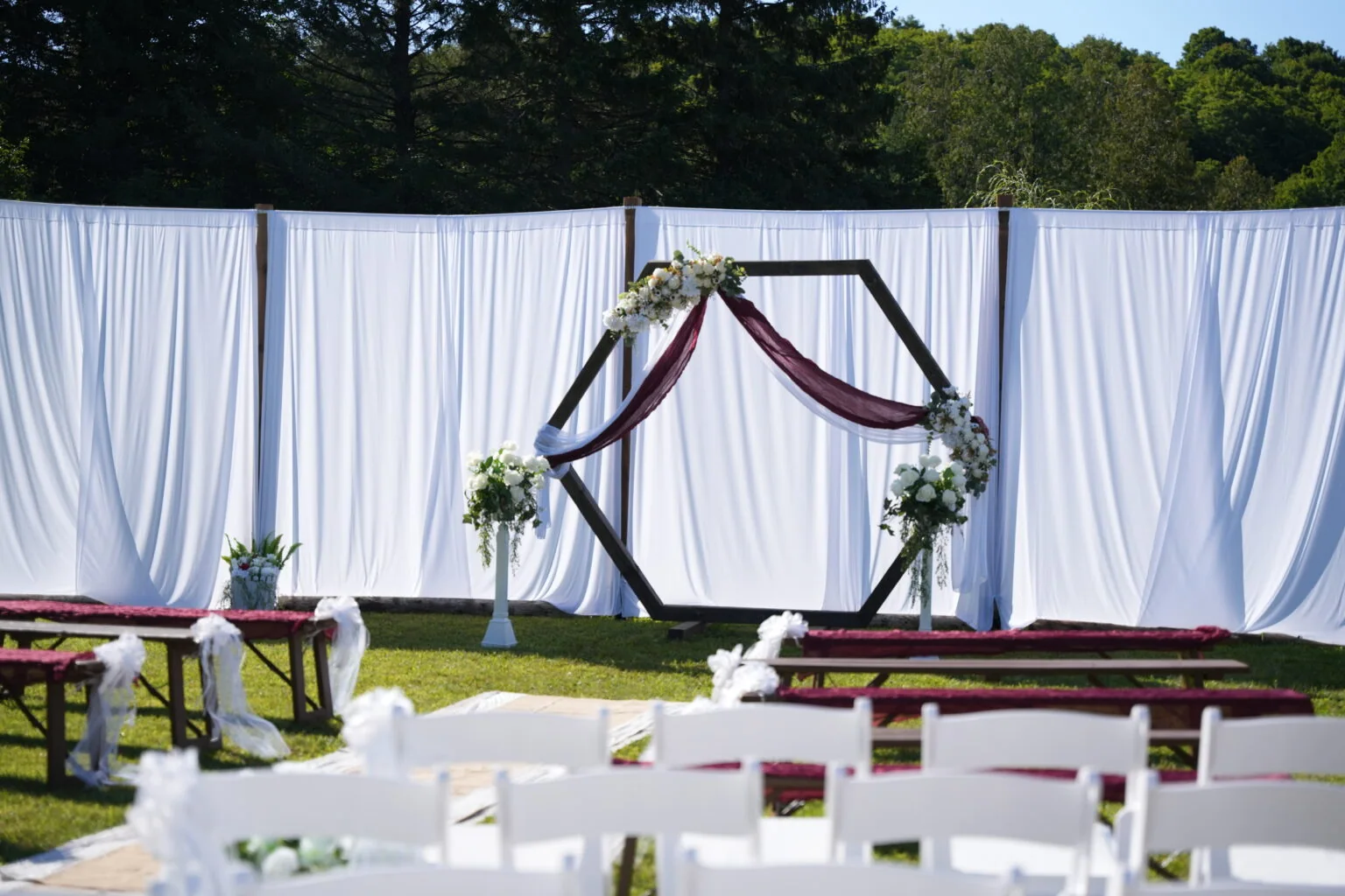 Chairs and a draped arch await guests at an outdoor ceremony.