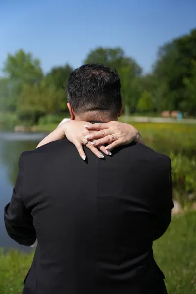 A couple embraces, photographed from behind the groom’s shoulder.