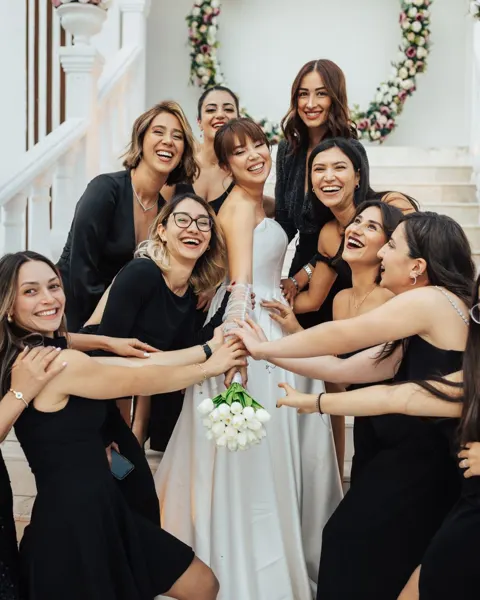The bride and her friends hug together in front of an entrance.