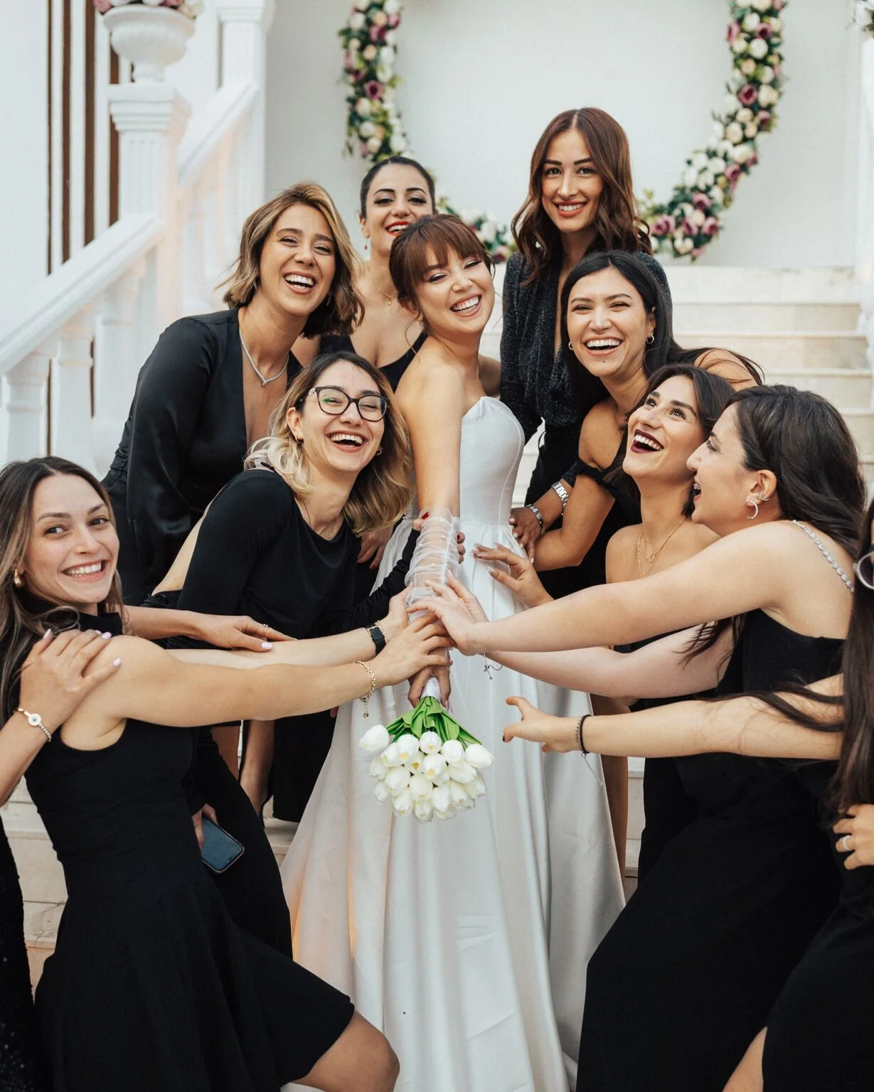 The bride and her friends hug together in front of an entrance.