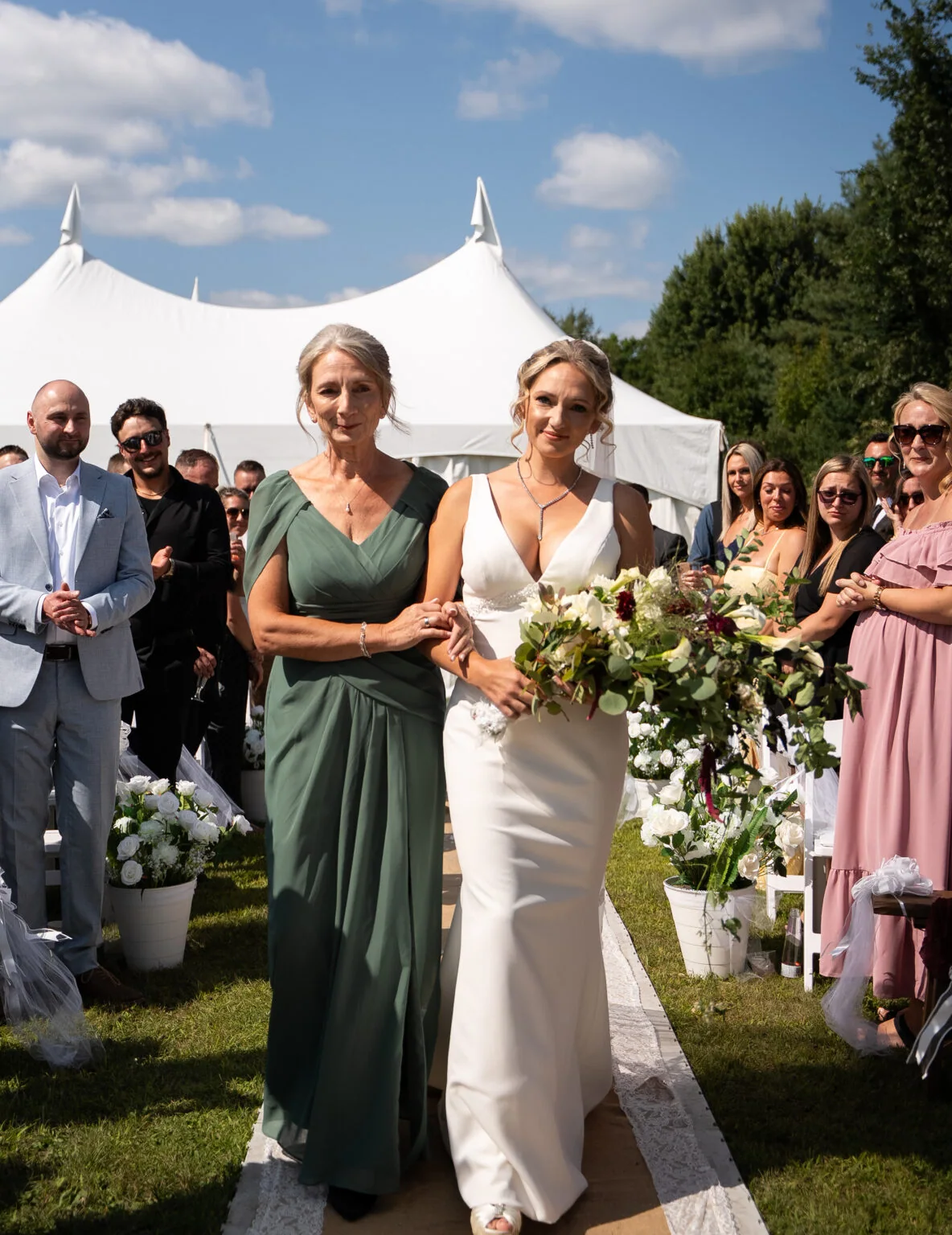 The bride walks with a loved one among the ceremony guests.