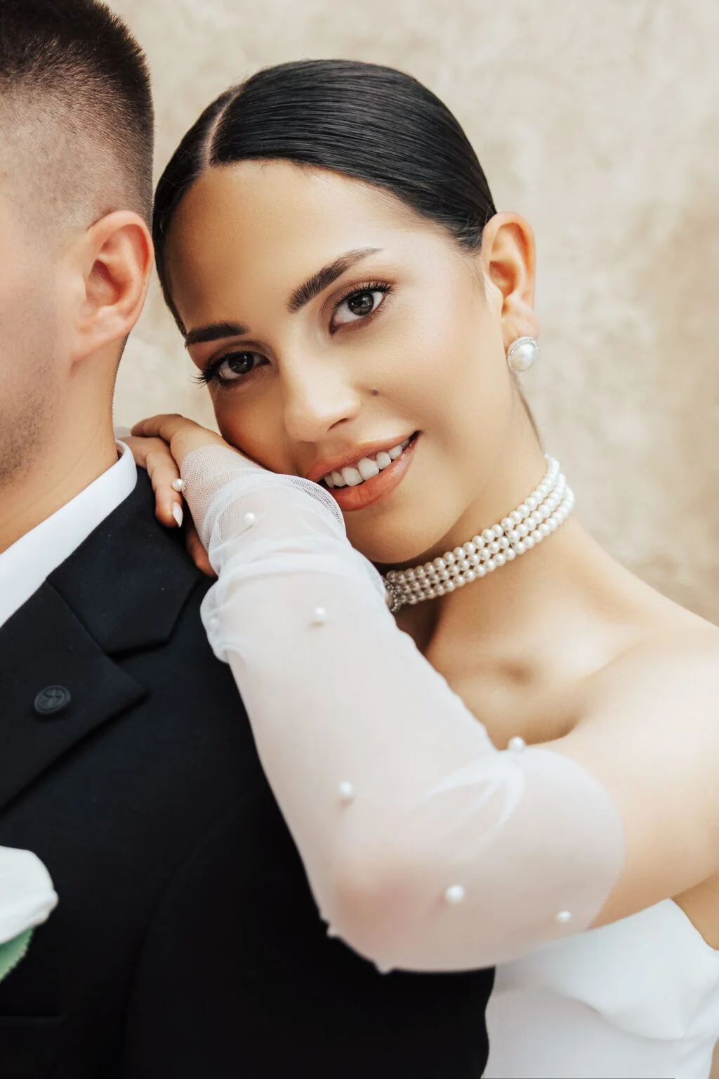 Portrait de la mariée en collier de perles, auprès de son partenaire.