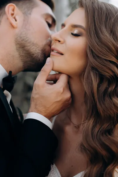 A close portrait of a couple sharing a kiss on the cheek.