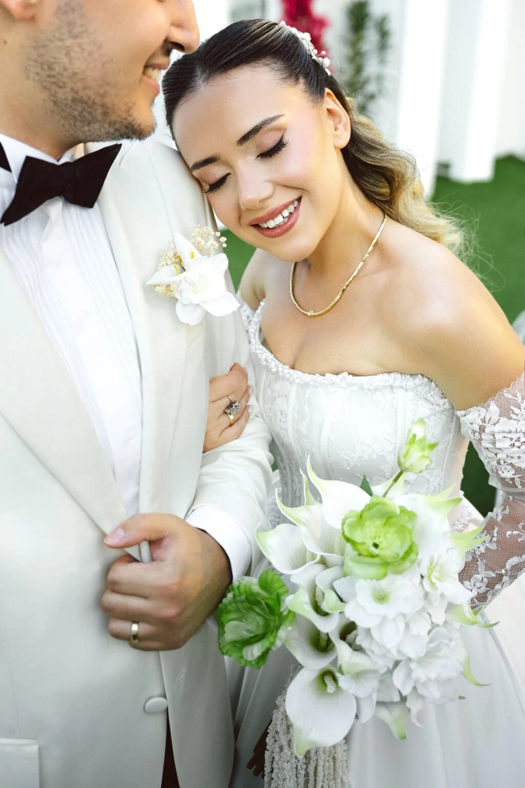 Close portrait of the newlyweds with a white bouquet and an off-the-shoulder gown.